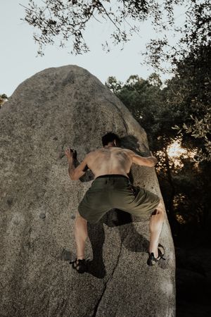 Man practicing rock climbing among large rocks in a forest