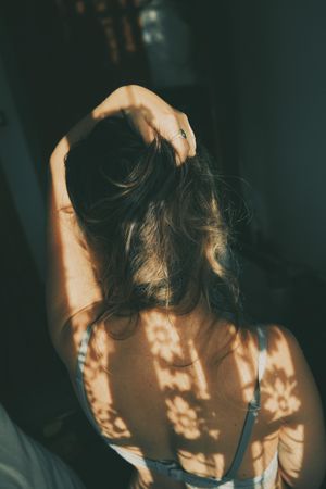 Back view of woman in gray bra with floral shadow on her