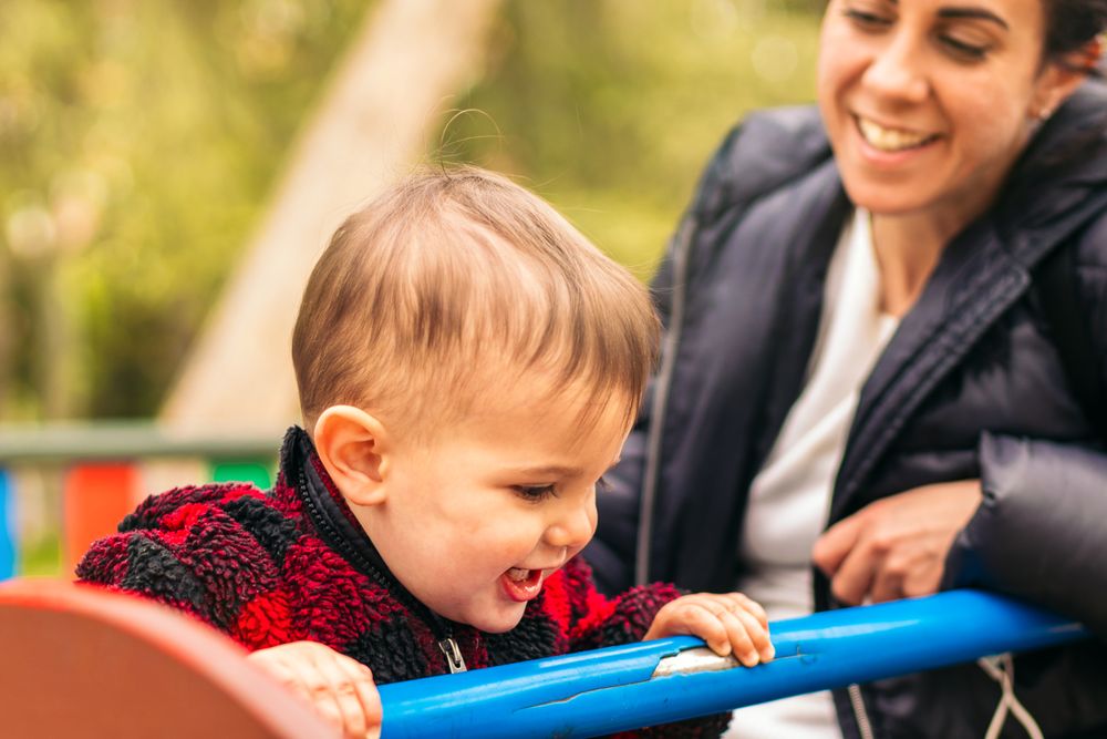 smiling mother and baby playing in a playground