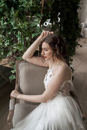 Side view of woman with red lips in white dress sitting on armchair