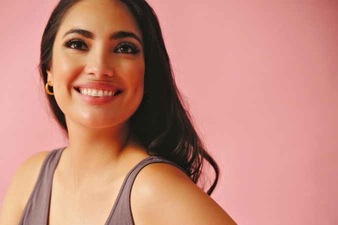 Smiling Hispanic woman looking at camera in pink room