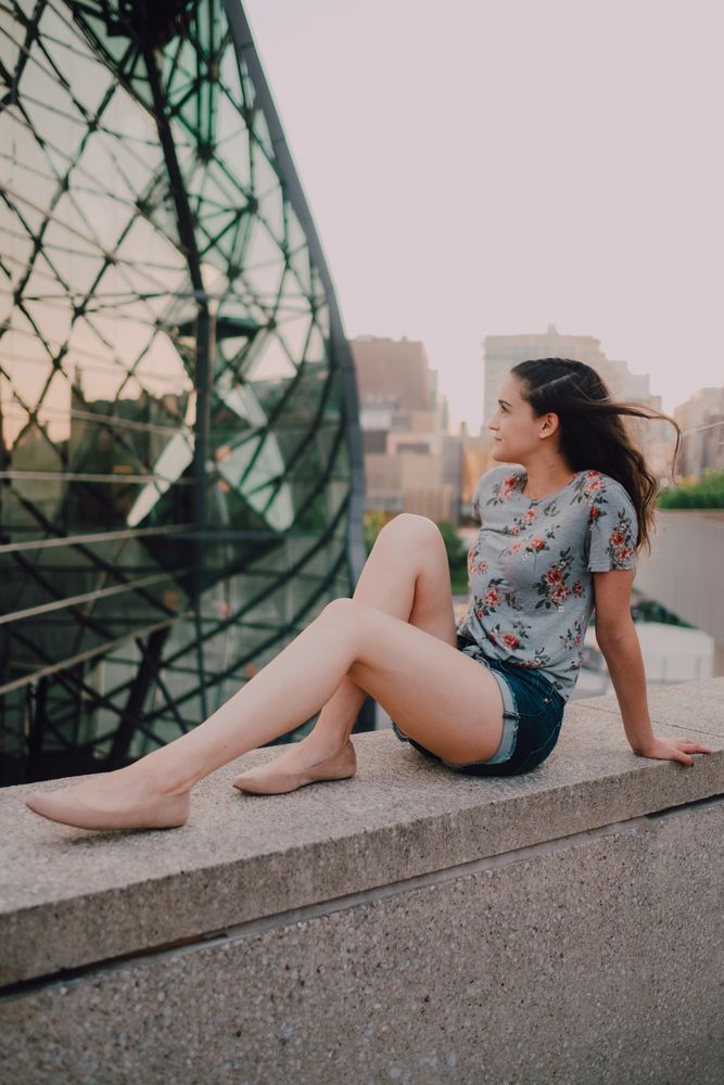 Smiling modern woman sitting on parapet