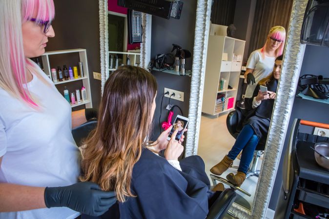 Woman showing hairdresser image on phone of what style she wants