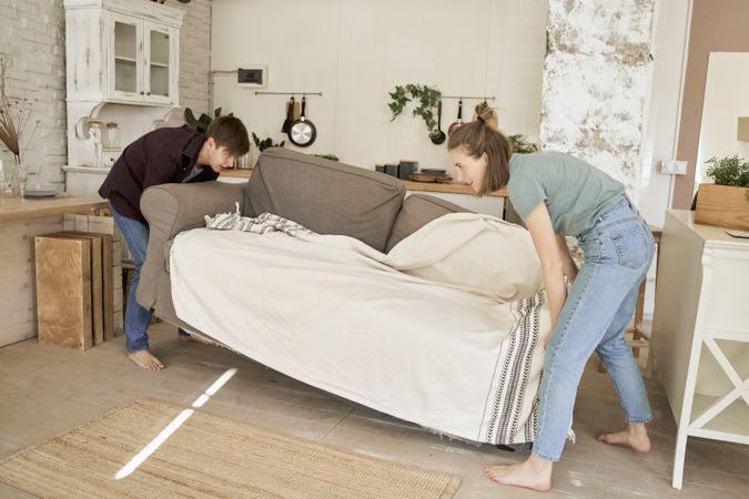 Energetic couple moving sofa into room together