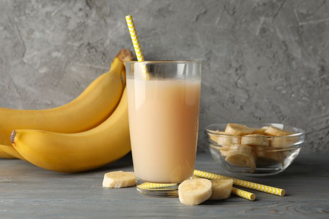 Bananas and juice against gray background. Fresh fruit