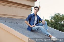 Male teenager in denim sitting on roof 4dl7a4