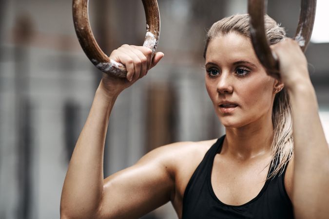 Focused woman holding onto gymnastic rings before workout