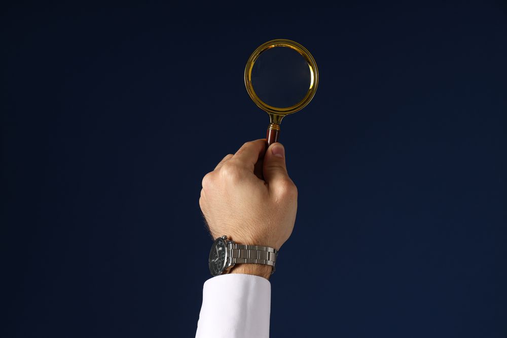 A businessman's hand holds a magnifying glass