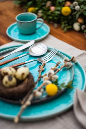 Festive table setting for Easter holiday dinner with bird nest & eggs with branch
