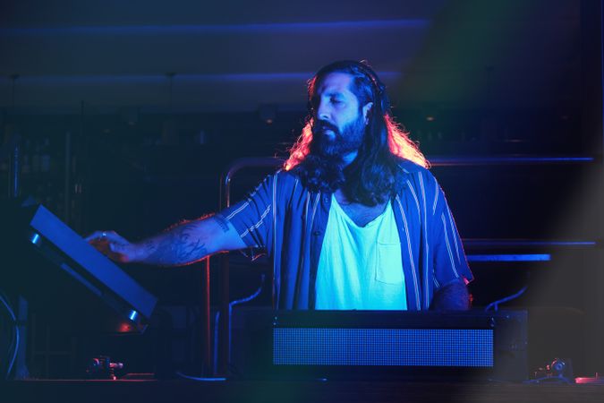 Male DJ playing music in dark club