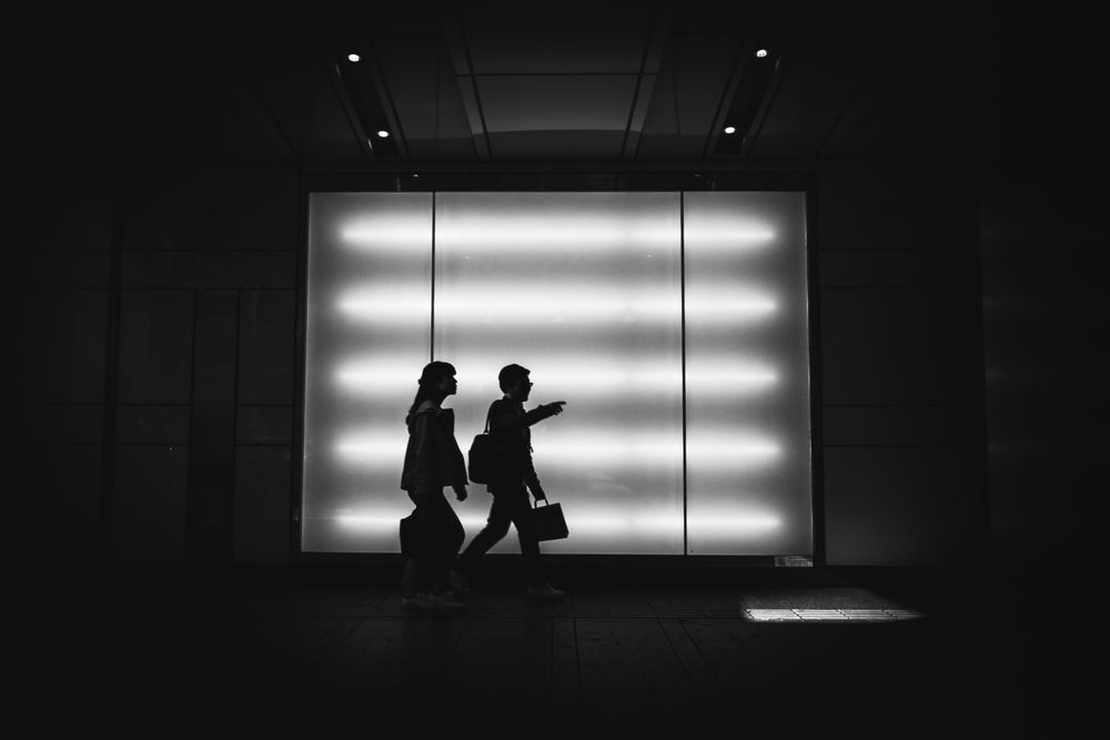 Silhouette of two people walking on hallway in grayscale