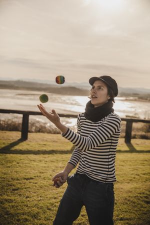 Woman juggling balls on meadow on shore