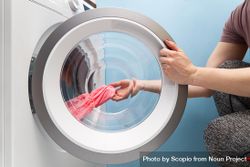 Person taking a piece of clothing out of a washing machine 0vWoB5