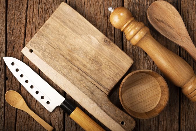 Cutting board with kitchen utensils on rustic background.