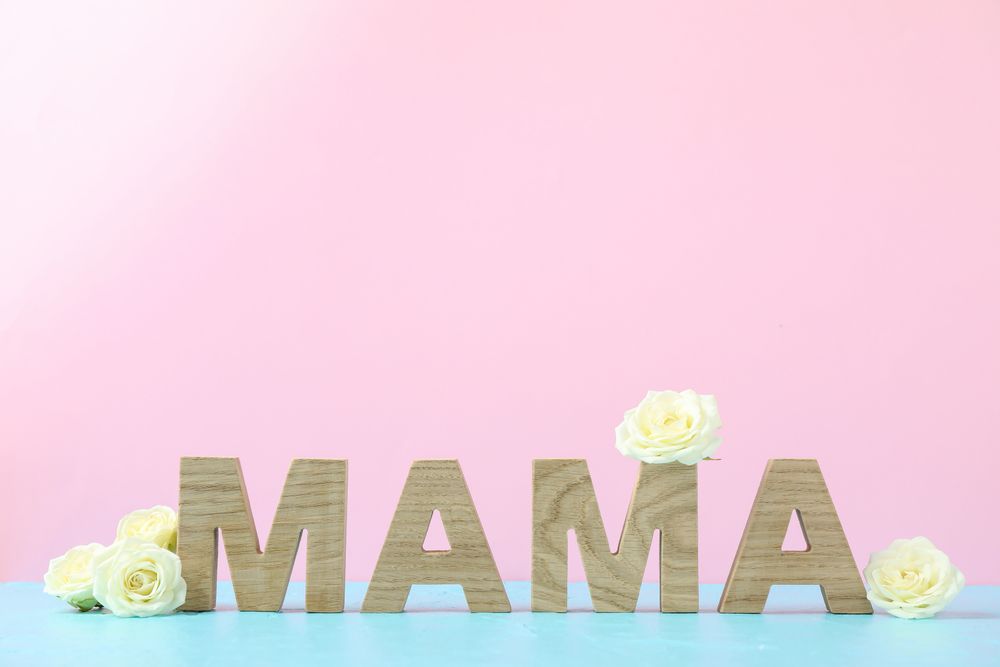 Inscription Mom with roses on blue table against color background, space for text