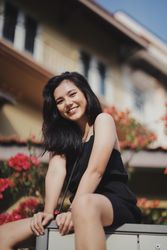 Woman in dark dress sitting on concrete bench near flower garden outdoor