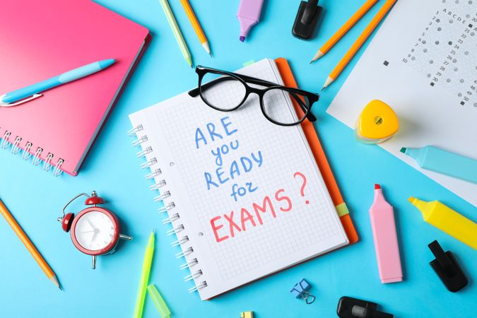 “Are you ready for exams” written in notebook on blue background with stationary