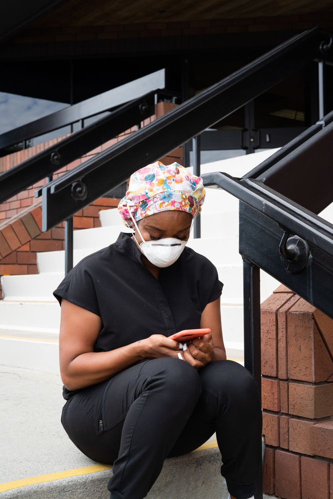 Woman nurse takes a break from shift looking at smart  phone