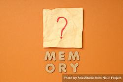 The word “Memories” written in cork below post it note on dusty orange background 4O6Lo5