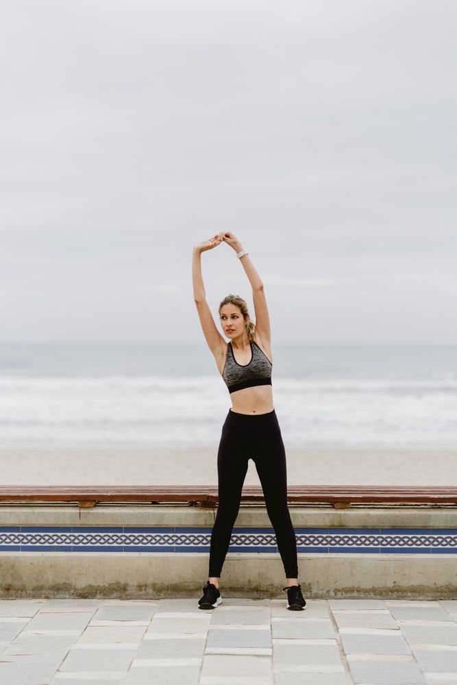 Woman in sports clothing stretching before exercise at seaside