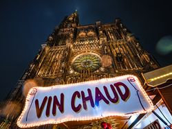 Hot wine "vin chaud" sign at Christmas market under gothic church in Alsace