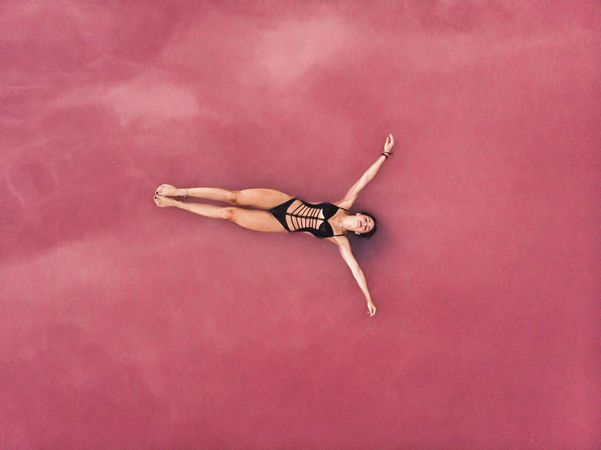 Carefree woman on vacation delighting in pink water of lake