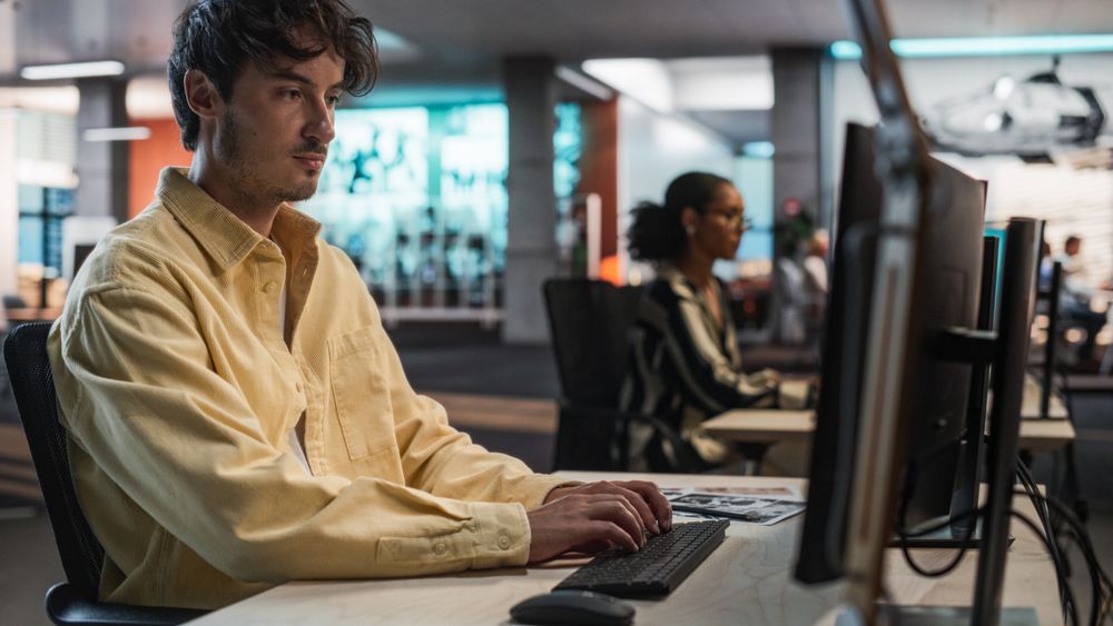 Male Game Programmer Coding On Desktop Computer In Game Design Studio Diverse Office.