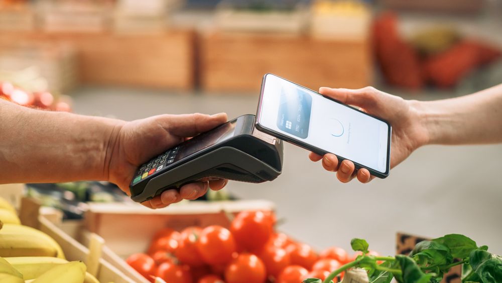 Consumer Buying Organically Sourced Farm Produce Using a Digital Credit Card to Pay with a Smartphone Software Through Contactless Online NFC Technology on a Bank Point-Of-Sale Terminal
