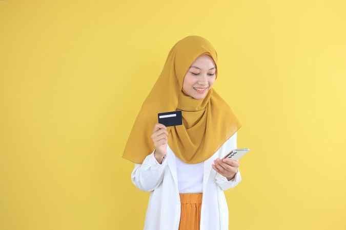 Asian Young Muslim Female Holding Credit Card and Mobile Phone