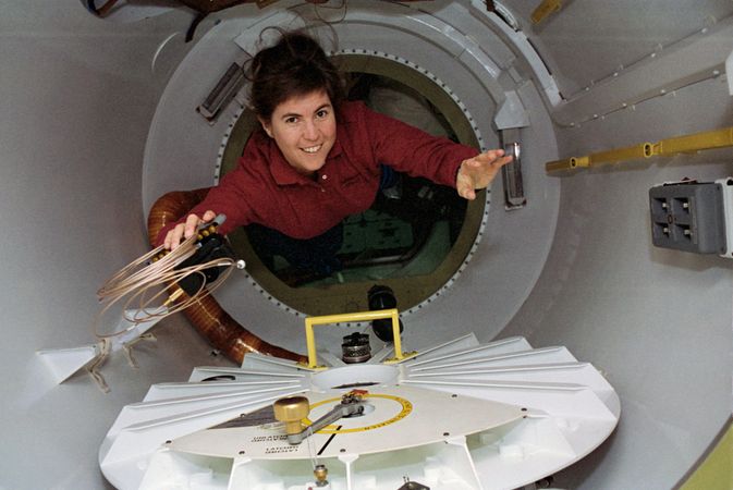 Astronaut Janice Voss floating with a camera and cable in hand