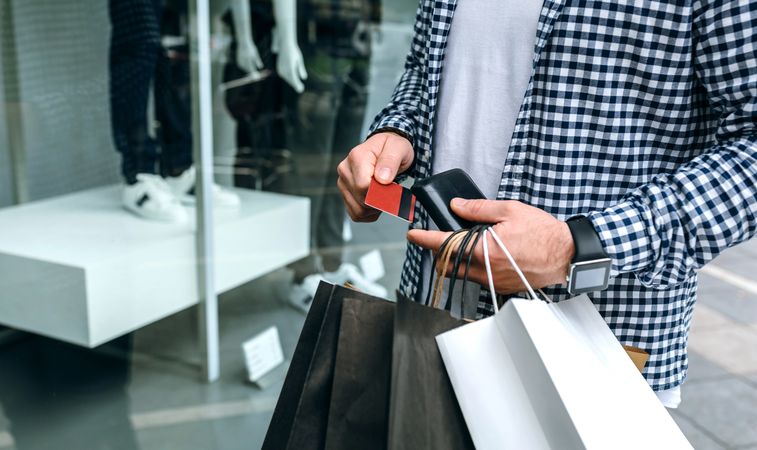 Man taking out credit card window shopping