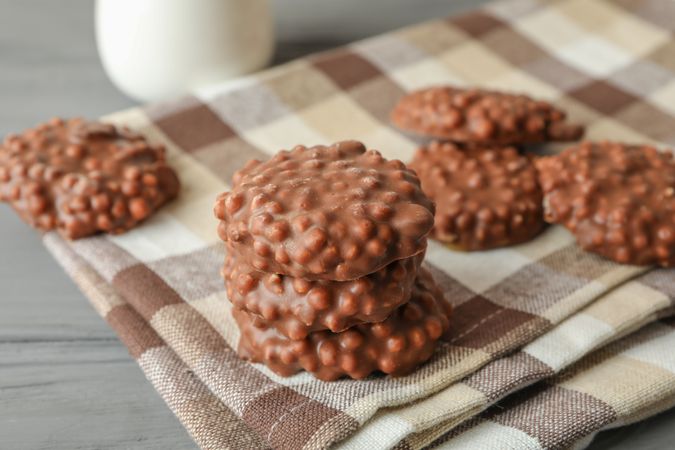 Kitchen towel with stack of chocolate cookies on grey table, space for text