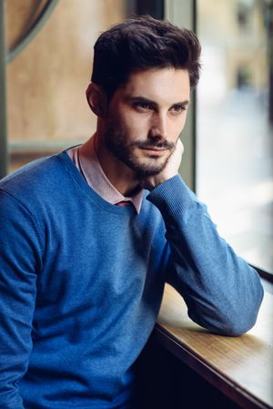 Man in sweater sitting in window of cafe