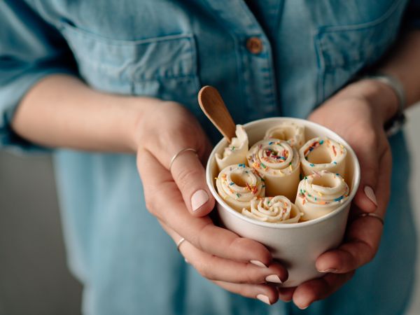 Hand holding rolled ice cream in cone cup