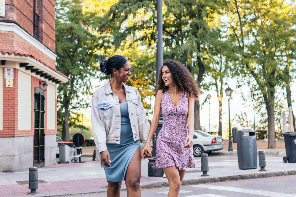 Two women crossing the pedestrian crossing in the city.