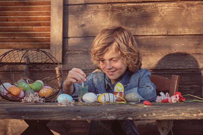 Little smiling boy with Easter eggs and paints