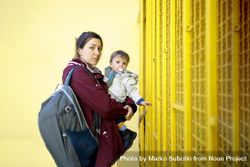 Side view of a woman holding her child in front of yellow wall beRmE0