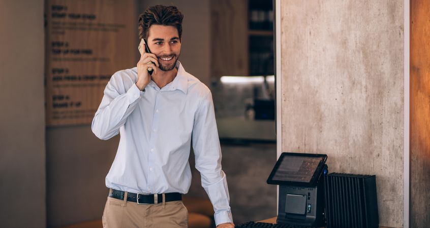 Young businessman standing in a cafe and talking on phone