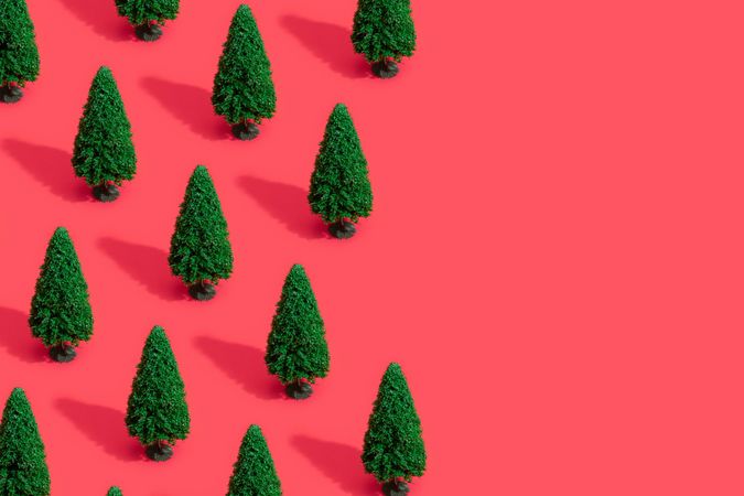 Green Christmas trees on bright salmon red background