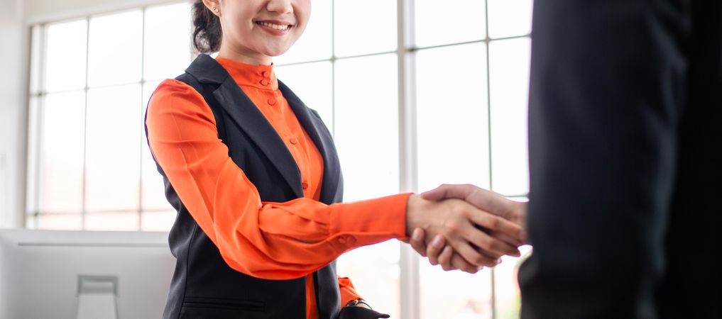 Banner of woman in orange blouse reaching out to shake someone’s hand