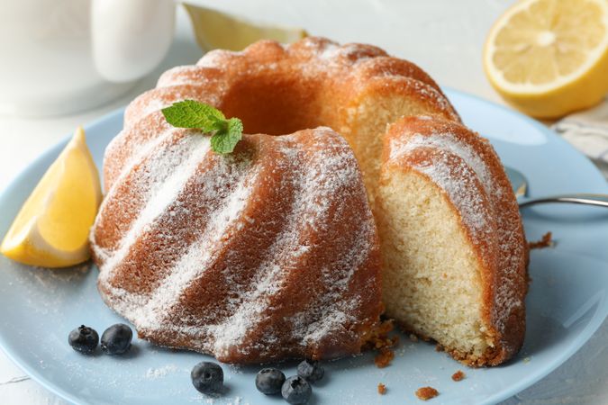 Cake with powdered sugar, blueberry and mint on plain background, close up