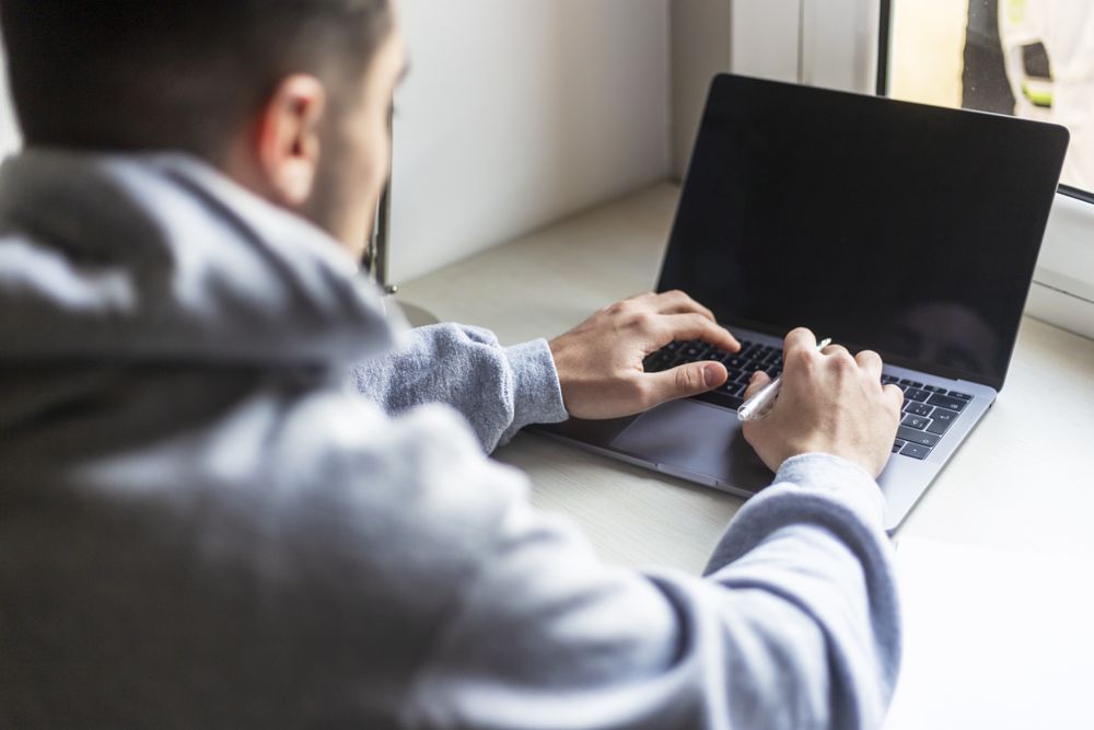 Rear view of a man working on laptop at home