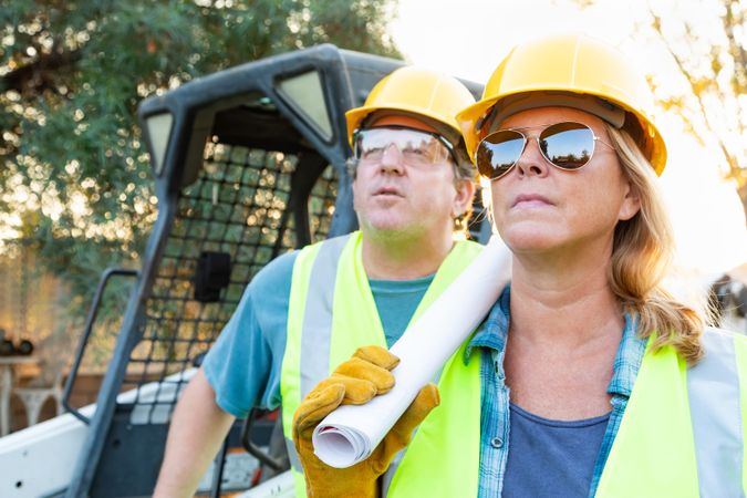 Male and Female Workers With Technical Blueprints at Construction Site