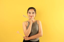 Asian Young Woman Holding Make Up Brush Smiling to the Camera