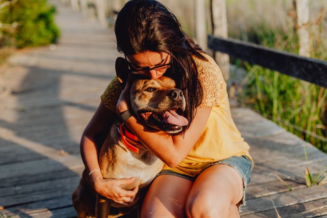 Happy adult woman hugging dog at countryside