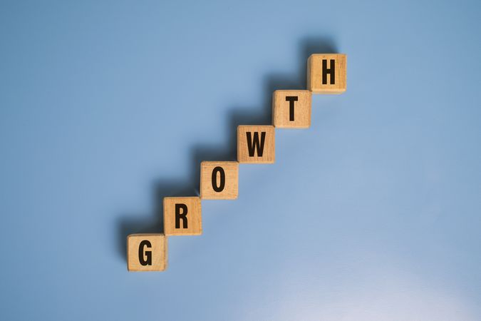 growth word on raise staircase wooden blocks isolated on blue background