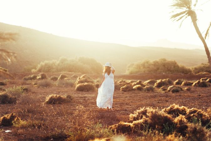 Woman in white dress in dry field in sunlight