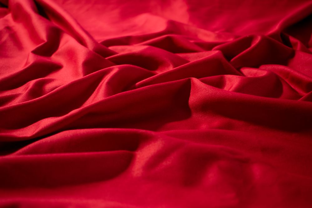 Crumpled wavy Red silky fabric background texture.
