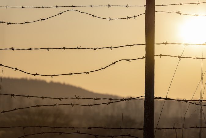 Sunrise behind a barbed-wire fence