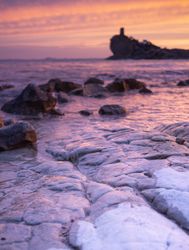 Sundown sky over sea and stony coast